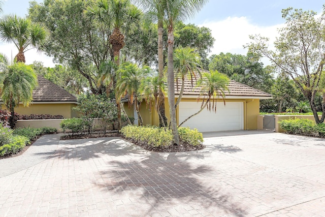 view of front of home with stucco siding, decorative driveway, and fence