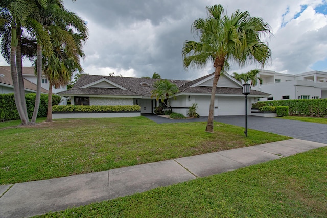 view of front of house with a front lawn, an attached garage, and driveway