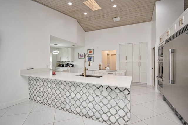 kitchen featuring wood ceiling, light tile patterned floors, appliances with stainless steel finishes, a peninsula, and white cabinetry