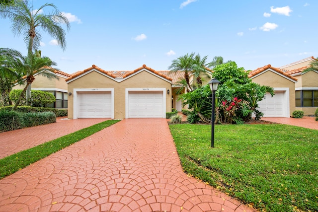 mediterranean / spanish house featuring a tile roof, a front lawn, and stucco siding