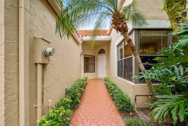 property entrance featuring a tiled roof and stucco siding