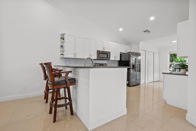 kitchen featuring dark countertops, stainless steel microwave, visible vents, and black fridge