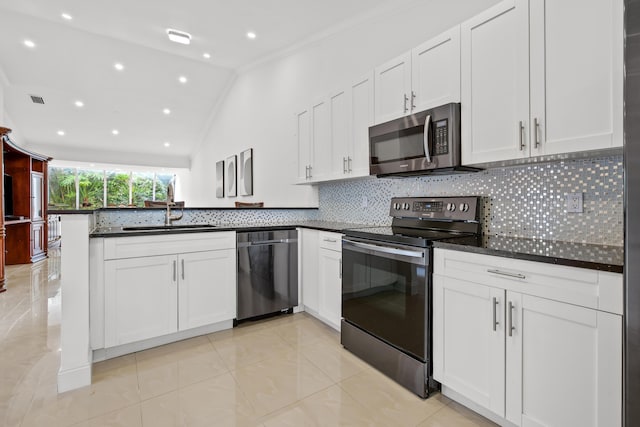 kitchen with a peninsula, a sink, white cabinetry, appliances with stainless steel finishes, and backsplash