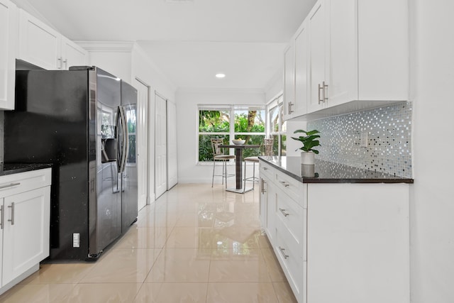 kitchen featuring white cabinetry, ornamental molding, backsplash, stainless steel fridge with ice dispenser, and dark countertops