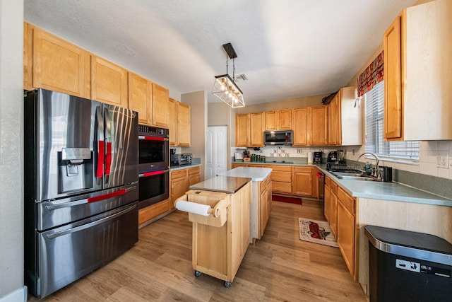 kitchen featuring light wood-style flooring, a sink, stainless steel appliances, backsplash, and a center island