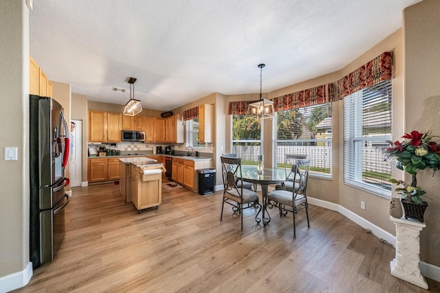 kitchen with a sink, stainless steel appliances, light countertops, and light wood finished floors