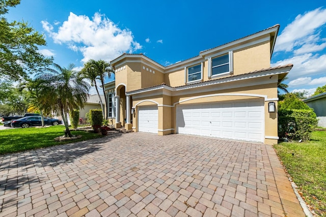 view of front of house with stucco siding, decorative driveway, and an attached garage