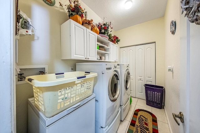 washroom featuring light tile patterned floors, cabinet space, separate washer and dryer, and a textured ceiling