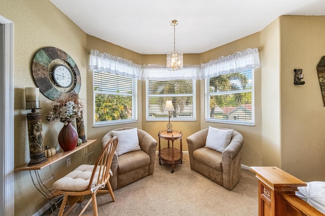 living area featuring carpet flooring, a textured wall, baseboards, and a chandelier