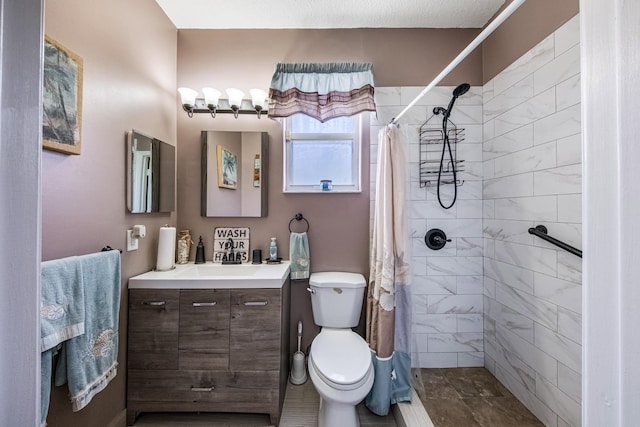 full bathroom with a tile shower, toilet, and vanity