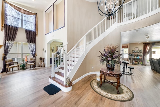 entrance foyer featuring arched walkways, stairway, baseboards, and wood finished floors