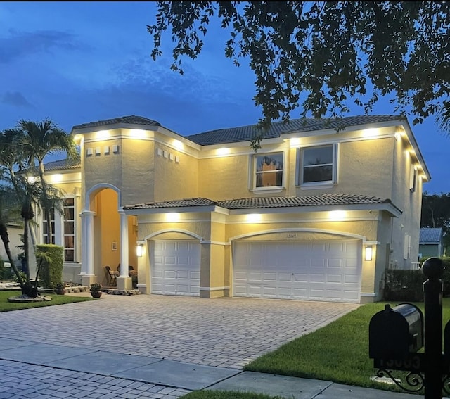 view of front facade featuring stucco siding, decorative driveway, an attached garage, and a tile roof