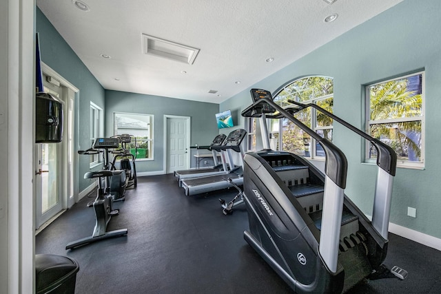 exercise room featuring a textured ceiling and baseboards