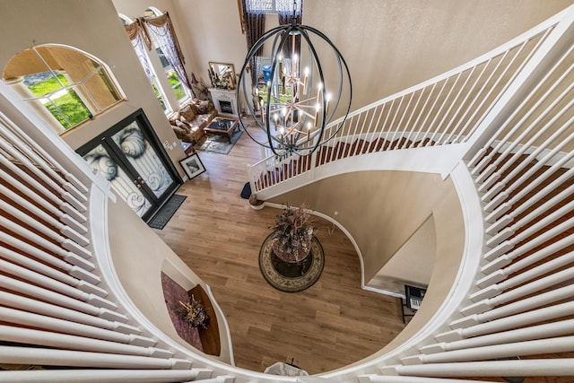 stairs with a notable chandelier, wood finished floors, and a towering ceiling