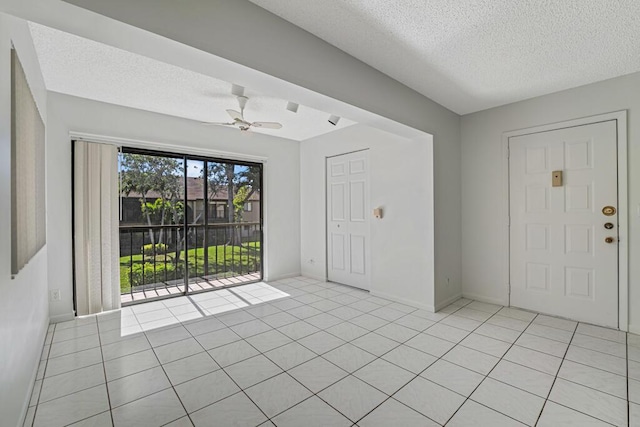 unfurnished room with a textured ceiling, ceiling fan, light tile patterned floors, and baseboards