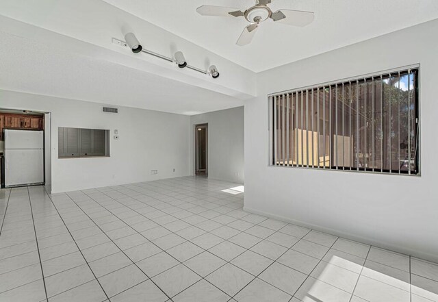 empty room featuring light tile patterned floors, visible vents, and a ceiling fan