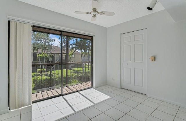 tiled empty room featuring a ceiling fan, a textured ceiling, and baseboards