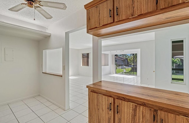 hallway featuring light tile patterned floors, a textured ceiling, and baseboards