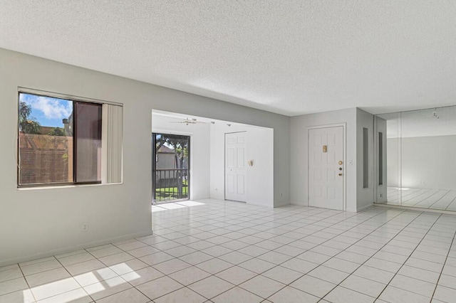 unfurnished room featuring a textured ceiling, baseboards, and light tile patterned floors