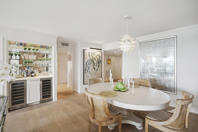 dining area featuring a bar, wine cooler, visible vents, and light wood-style floors