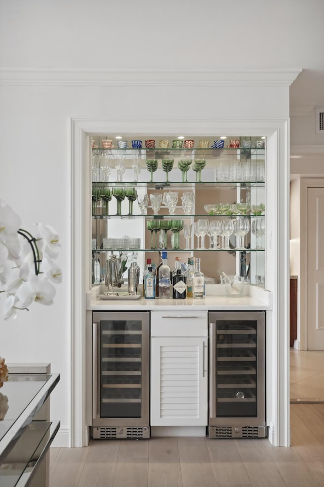 bar featuring ornamental molding, wine cooler, and a bar