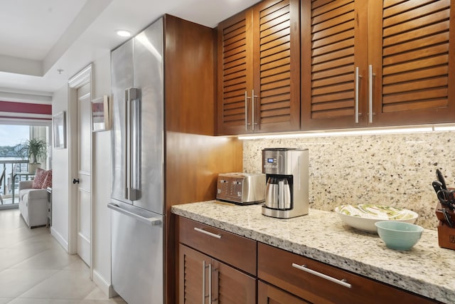 kitchen with light tile patterned floors, decorative backsplash, and light stone countertops