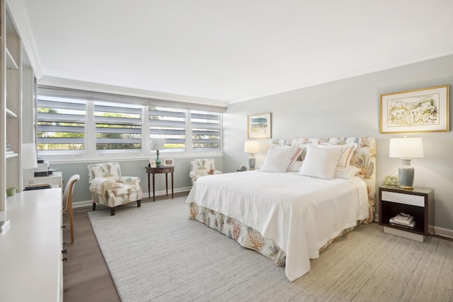 bedroom featuring baseboards, wood finished floors, and crown molding