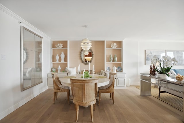 dining room featuring baseboards, crown molding, and light wood finished floors