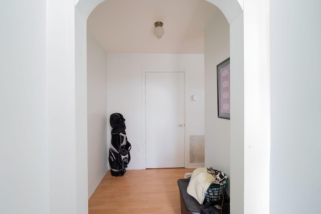 hallway with arched walkways, visible vents, and light wood-style floors