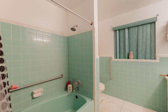 bathroom with wainscoting, toilet, tile patterned flooring, washtub / shower combination, and tile walls