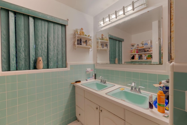 full bath featuring double vanity, a wainscoted wall, tile walls, and a sink