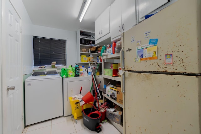 washroom with light tile patterned floors, washing machine and dryer, and cabinet space