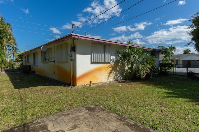 view of property exterior featuring central AC, a lawn, and fence