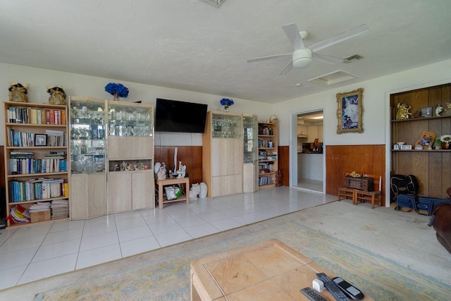 interior space with a wainscoted wall, wooden walls, visible vents, and a ceiling fan