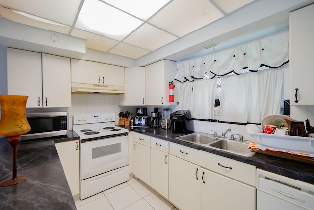 kitchen with white appliances, a drop ceiling, a sink, under cabinet range hood, and backsplash