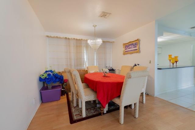 dining room with a chandelier, wood finished floors, visible vents, and baseboards