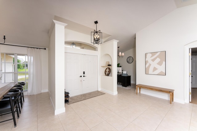 entrance foyer with a chandelier, light tile patterned flooring, lofted ceiling, and baseboards