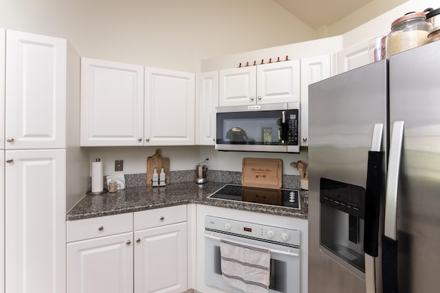 kitchen featuring stainless steel appliances, white cabinets, and dark stone countertops