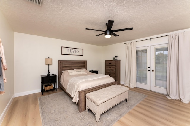 bedroom featuring light wood-style flooring, ceiling fan, access to exterior, a textured ceiling, and french doors