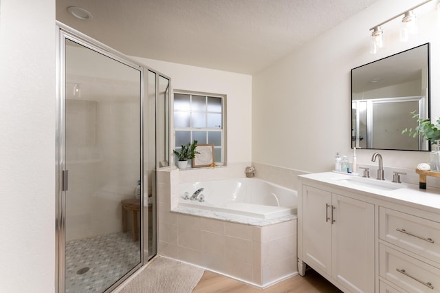 bathroom with a stall shower, a garden tub, wood finished floors, and vanity