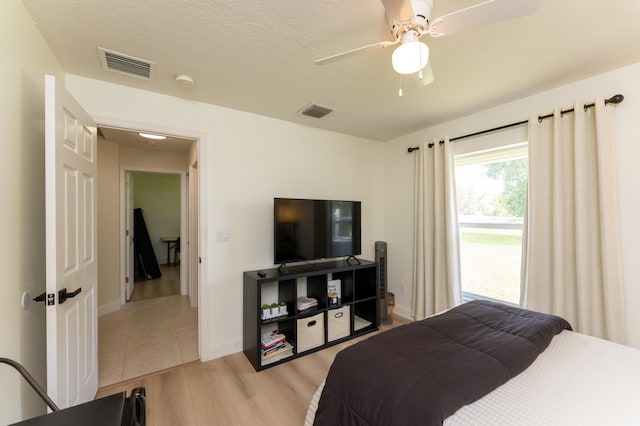 bedroom with a ceiling fan, baseboards, visible vents, and light wood finished floors