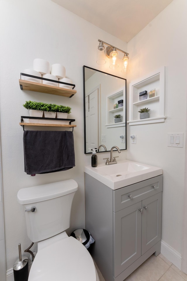 half bathroom with toilet, tile patterned flooring, vanity, and baseboards