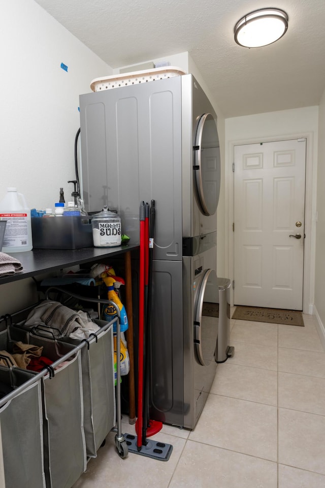 clothes washing area featuring laundry area, light tile patterned floors, and stacked washer and clothes dryer