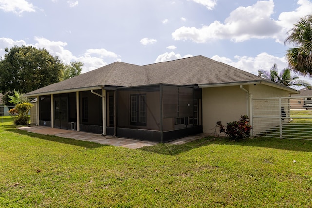 back of property featuring a sunroom, a shingled roof, stucco siding, and a yard