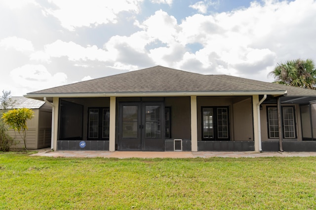 rear view of house featuring french doors, a yard, stucco siding, a shingled roof, and a sunroom