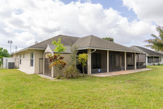 back of house with central air condition unit, fence, and a yard