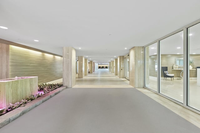 corridor with recessed lighting, concrete flooring, and a wall of windows