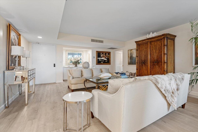 living area featuring light wood-type flooring, visible vents, and baseboards