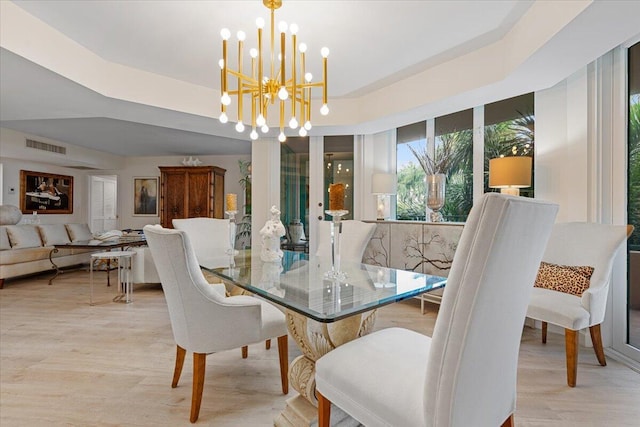 dining area featuring an inviting chandelier, visible vents, light wood-type flooring, and a tray ceiling