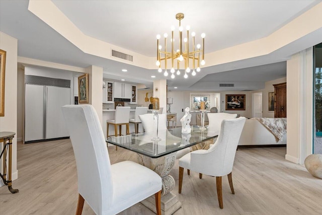 dining area featuring visible vents, baseboards, an inviting chandelier, a tray ceiling, and light wood-style floors